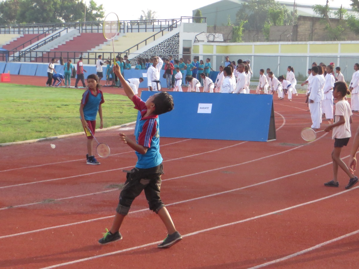 Kids playing badminton, with karate and athletics groups in the background
